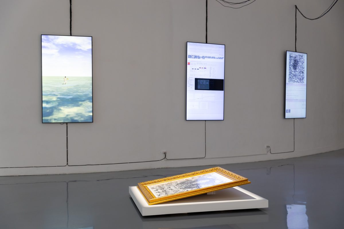 LUCKY39 installation at BACC, with three suspended screens and a framed map